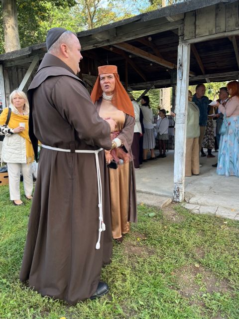 Franciszkanin w rozmowie z gościnią w średniowiecznym stroju